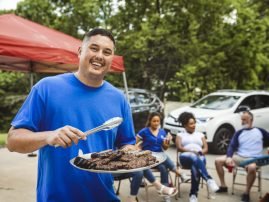 Man handing out burgers at a tailgate party